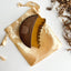 Wooden face brush on a gold satin bag with decorative elements on a light background